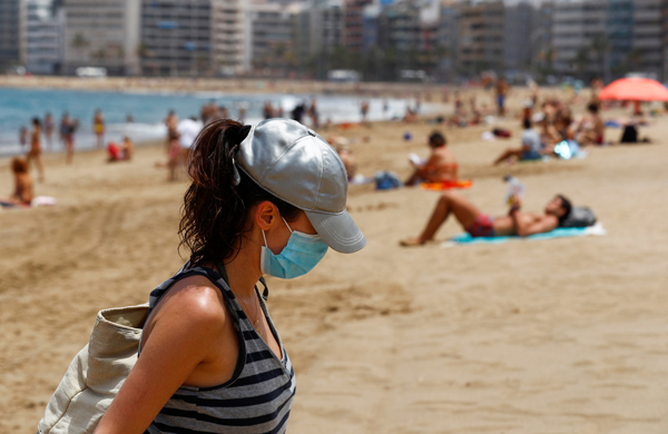 スペイン・グランカナリア島のビーチでマスクをつけ歩く女性