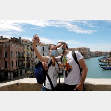 ヴェネチアの観光地で写真を撮るマスク姿の観光客