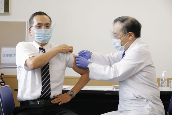 新型コロナウイルス感染症の国内１例目のワクチン接種を受ける、国立病院機構東京医療センターの新木一弘院長（左）
