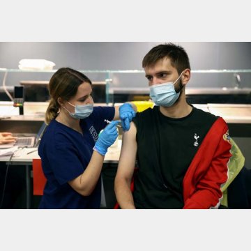 ファイザー製ワクチンを接種される若者（ロンドン＝トッテナム・ホットスパースタジアム）