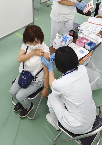 大規模接種会場でワクチン接種を受ける女性
