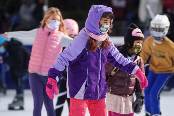 マスクを着けてブライアント公園でスケートを楽しむ子供たち