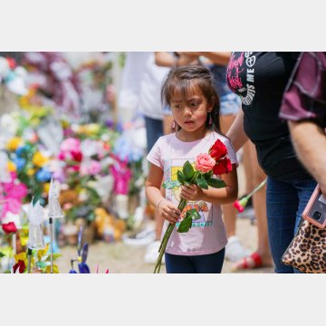 追悼に訪れ花をたむける少女