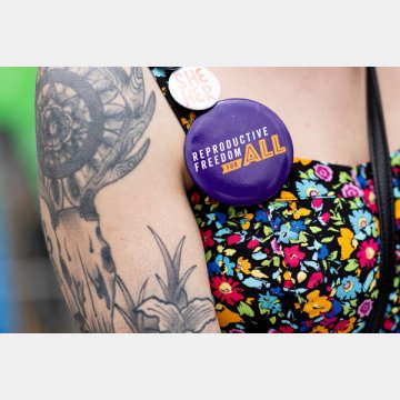 中絶修正案の署名活動を行う女性の胸についたワッペン