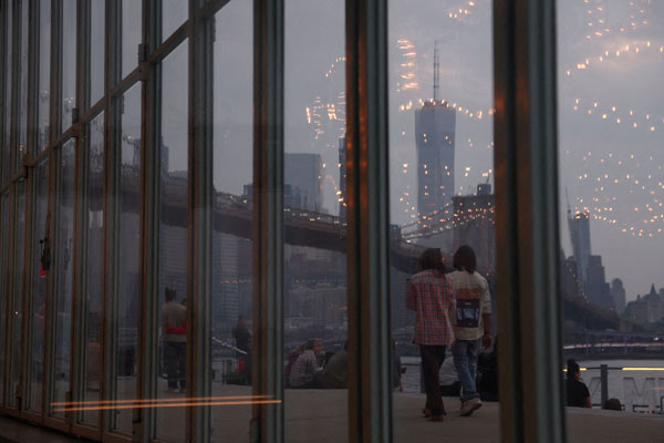 カナダの山火事によるもやと煙に覆われたマンハッタンのスカイラインを背景に歩く人々（Ｃ）ロイター