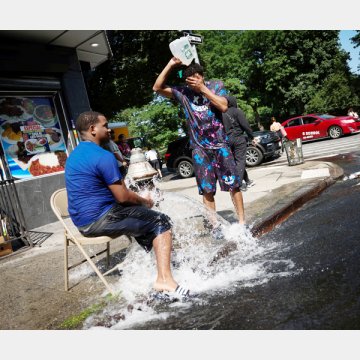 ニューヨーク市マンハッタンのワシントンハイツ地区で、消火栓の水で涼む若者たち（Ｃ）ロイター