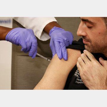 最新の新型コロナワクチンを接種する医師（Ｃ）ロイター